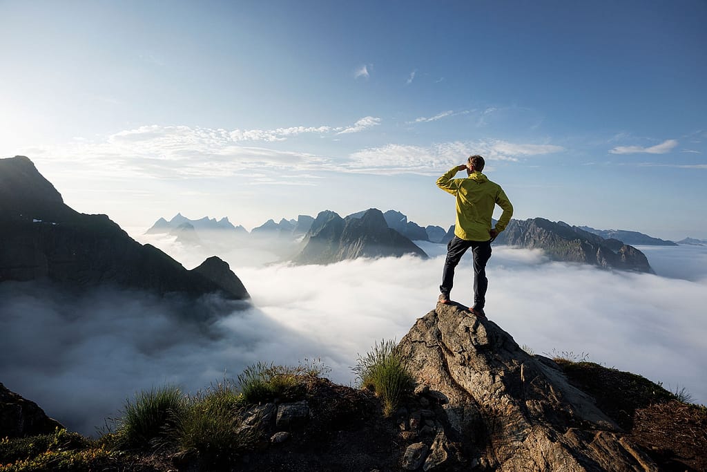 A guest from Havila Voyages visits a mountain top in Lofoten
