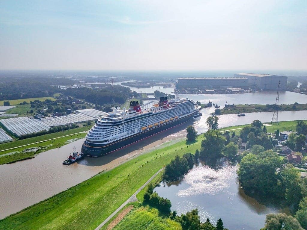 Disney Treasure being guided by Tug Boat down the Ems River